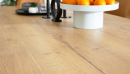 Heller Holztisch mit natürlicher Maserung, darauf Obstschale mit Orangen, modernes, minimalistisches Design.